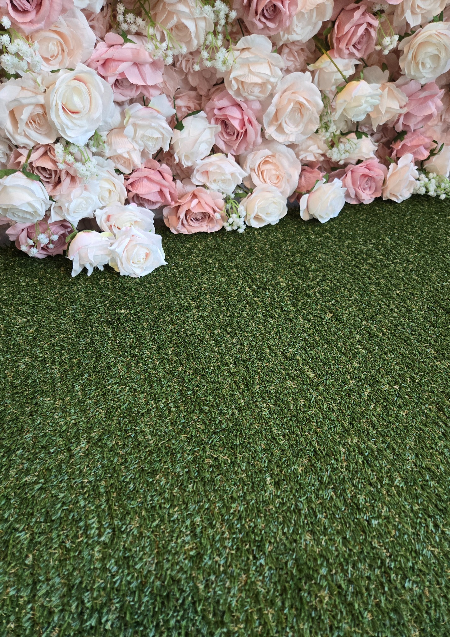 Faux grass carpet beneath blush flowers